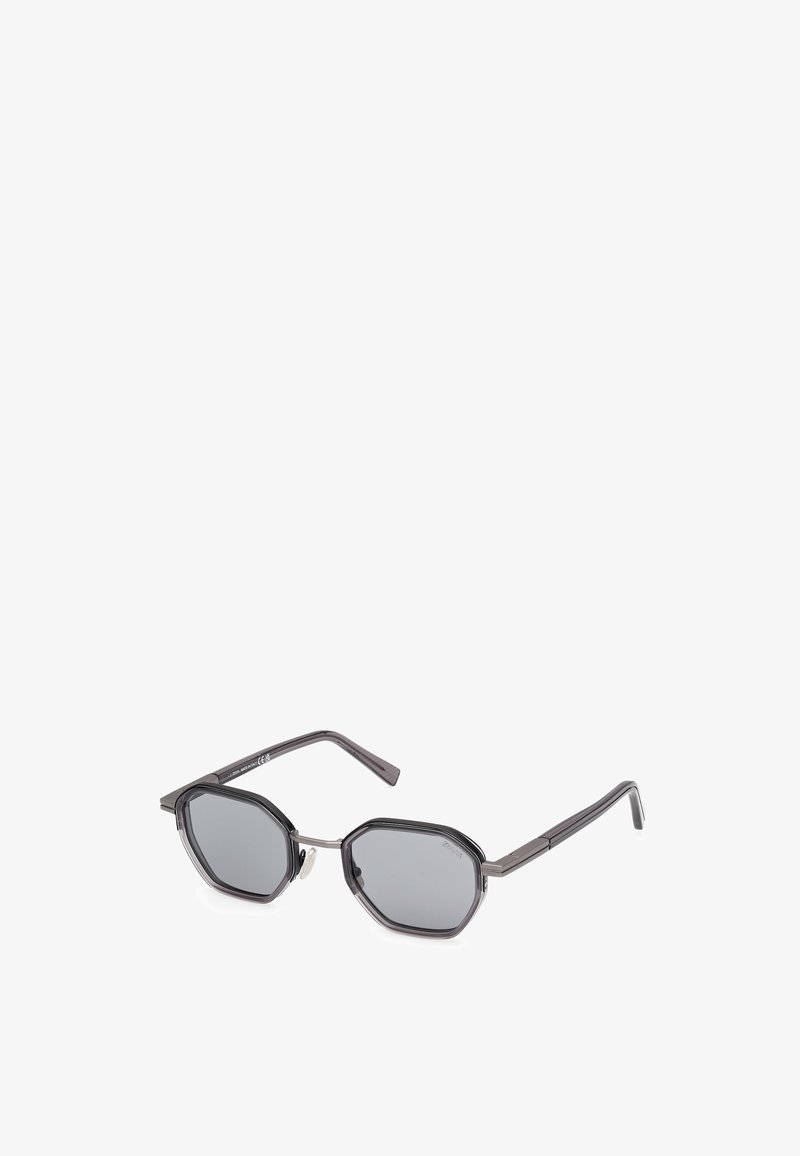 Ochelari de soare cu lentile octogonale gri, cadru din plastic de culoare gri închis, temple subțiri și accente argintii aproape de balamale.