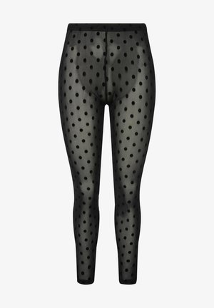 Leggings noirs à pois blancs fabriqués en matériau transparent, avec une taille élastique et un design ajusté et fuselé. Les pois sont espacés de manière uniforme.