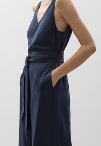Marinefarbendes ärmelloses Kleid aus einem Leinen-Mix, mit tiefem V-Ausschnitt, tailliertem Gurt, Seitentaschen und lockerer Passform.