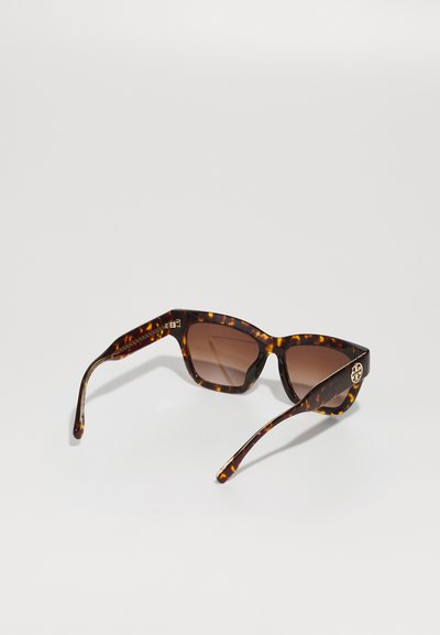 Lunettes de soleil en écaille de tortue avec des montures carrées, des verres bruns dégradés, un matériel doré décoratif sur les branches et une texture lisse et brillante.