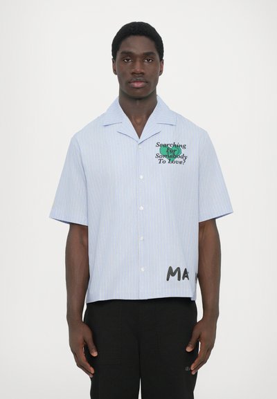 Camicia a maniche corte, a righe blu chiaro, con testo ricamato verde e dettagli neri. Chiusura a bottoni, vestibilità rilassata, con orlo corto.