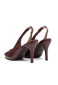 Burgundin nahasta valmistetut slingback-korkokengät, joissa on pyöreä kärki, avoimet sivut ja 10 cm:n stiletto-korko. Sisäpuolella on beige vuori ja brändäys.