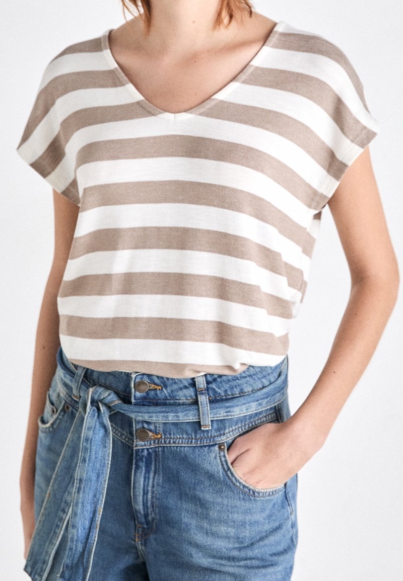 T-shirt léger en coton à rayures beige et blanc avec col en V et manches courtes, porté avec un short en denim bleu taille haute.