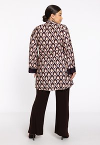 Langsleeve blouse in patroonstof met watervaldruppelontwerp in crème, roze en bordeauxrood. Heeft een ceintuur in de taille en contrasterende manchetten.