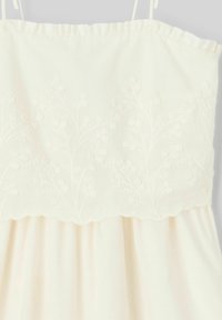 Robe blanche avec un design floral brodé sur le corsage, décolleté festonné et bas fluide en tissu léger.