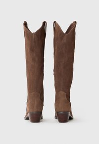 Brown suede cowboy boots with a pointed toe, high shaft, and decorative stitch patterns. The heels are stacked and slightly flared.