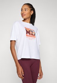 White cotton T-shirt with a cropped design featuring a colorful graphic print of faces and the word "FOREVER" in orange. Worn with maroon leggings.