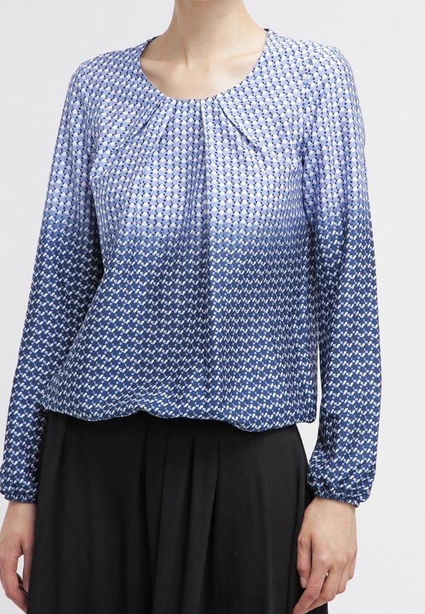 Blusa de manga larga en patrón degradado azul con escote plisado, que presenta una tela texturada y sutiles diseños geométricos.