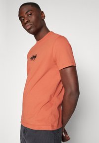 Calvin Klein CUT THROUGH LOGO - Apdrukāts T-krekls - copper sun