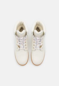 Bottes de cheville en cuir blanc avec doublure en peluche, bout arrondi et accents en métal doré. Elles disposent de lacets blancs avec une texture antidérapante.