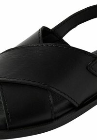 Sandal in pelle nera con fasce incrociate, punta aperta, suola piatta e dettagli cuciti. Texture liscia con finitura opaca.