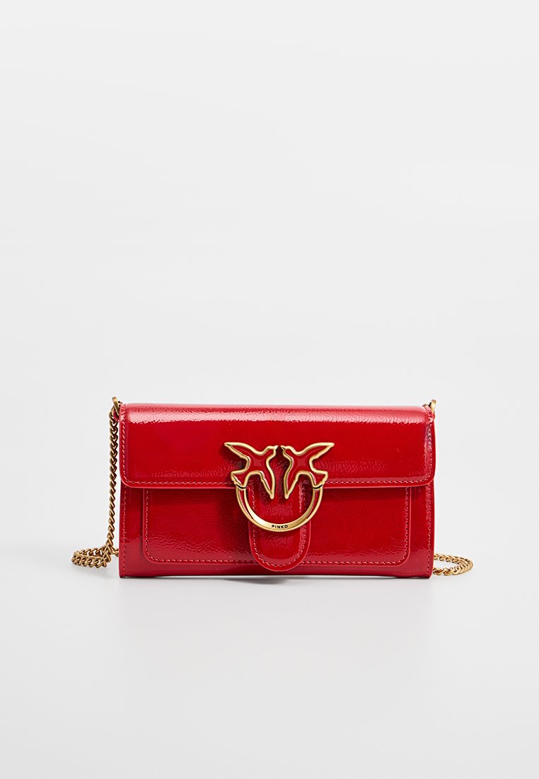 Czerwona torebka z lakierowanej skóry z złotym łańcuchem, z charakterystycznym zapięciem z logo i gładką teksturą. Kompaktowy prostokątny kształt.