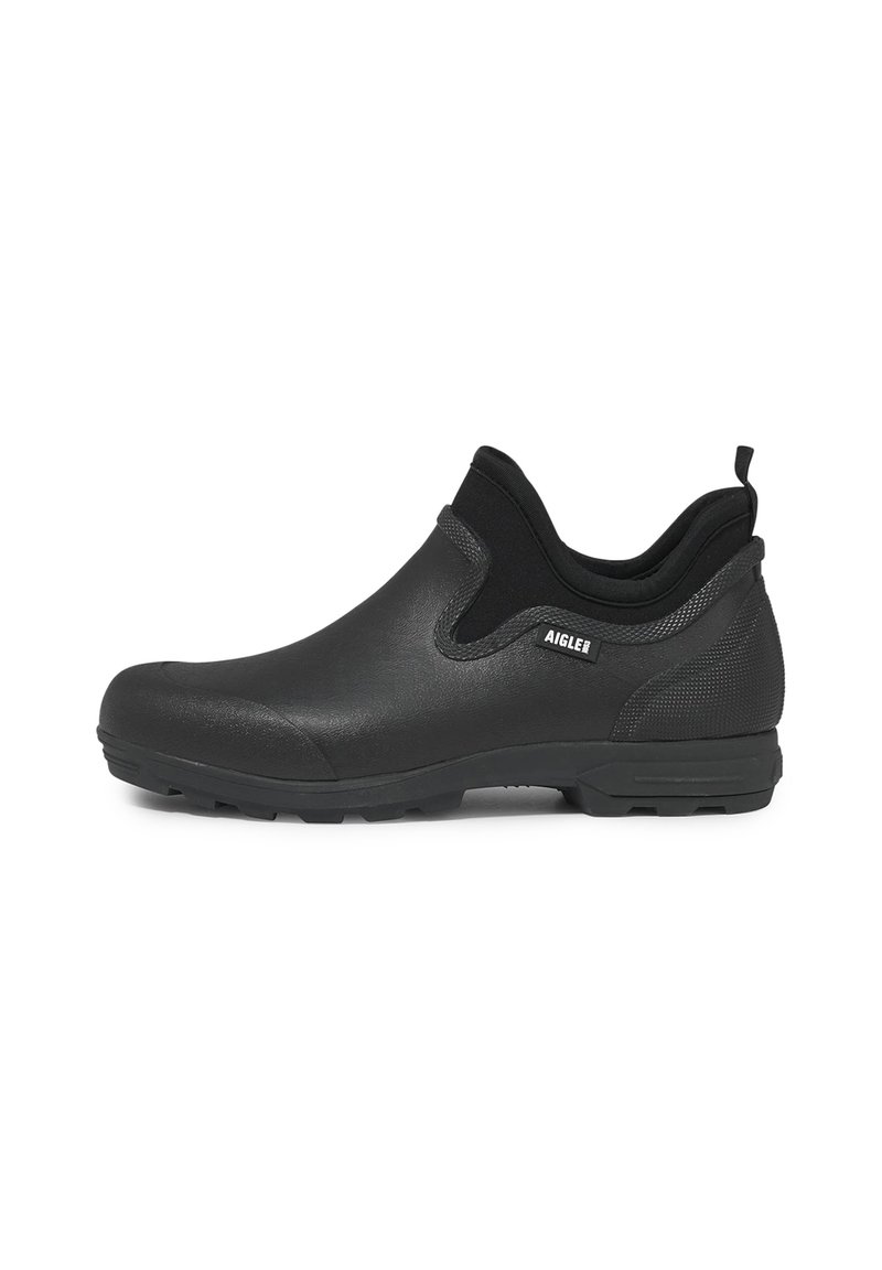 Chaussure noire imperméable à enfiler avec une finition lisse et mate, des côtés texturés et une semelle extérieure robuste pour l'adhérence. Équipée d'une languette pour un enfilage facile.