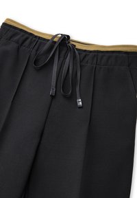 Zwarte broek met een elastische tailleband en een gouden accent. Beschikt over een trekkoord, een gladde textuur en een geplooid ontwerp.