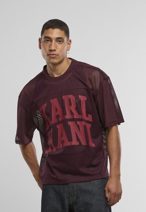Vinrød net-t-shirt med fed "KARL KANI" tekst i kontrastfuld rød, korte ærmer og mesh-paneler i siderne for ventilation.