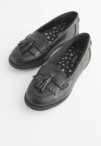 Mocasini din piele neagră, cu o panou decorativ din franjuri și accente cu ciucuri. Interiorul prezintă o căptușeală din țesătură cu tipar în stele. Design cu vârf rotunjit.