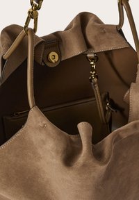 Borsa in suede taupe morbido con hardware dorato, caratterizzata da una parte superiore arricciata, una tasca interna con zip e dettagli in pelle liscia per una maggiore durata.