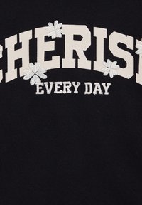 Svart sweatshirt med "CHERISH" och "EVERY DAY" i krämfärgade fetade bokstäver, prydd med vita broderade blommor som detaljer. Tillverkat i bomull.