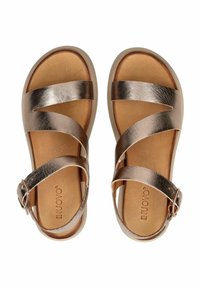 Bronzen metallic leren sandalen met kruissbandjes, een gevoerde tan binnenzool en verstelbare gespsluiting. Ontwerp met een platte zool.