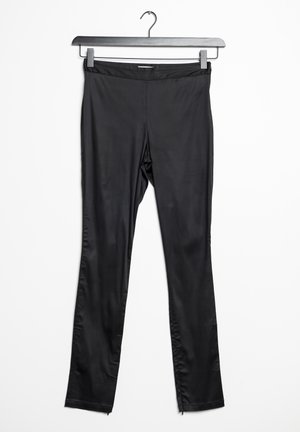 Leggings negros hechos de un material suave y elástico, con un diseño ajustado, piernas largas y cremalleras en los dobladillos de los tobillos.