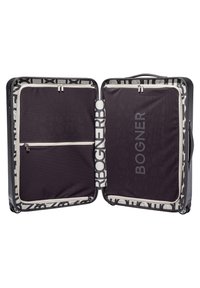 Maleta rígida negra con interior con estampado, compartimentos dobles, bolsillo con cremallera y el logo "BOGNER" bien visible.