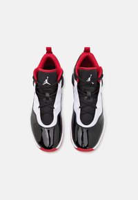 Paire de chaussures de basketball montantes noires, blanches et rouges avec embouts brillants et logo Jumpman sur languettes en mesh noir.