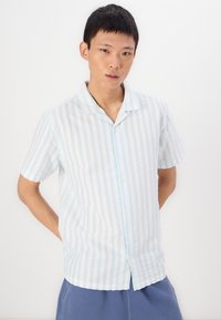 Camicia a maniche corte con bottoni in blu chiaro e righe bianche, realizzata in tessuto leggero, con una vestibilità rilassata e un colletto alla carina.