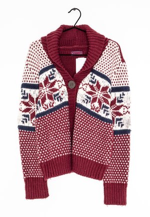 Cardigan tricoté bordeaux, blanc et bleu marine avec de grands motifs flocons de neige, col et poignets côtelés, bouton unique à l'avant, accroché à un cintre noir.
