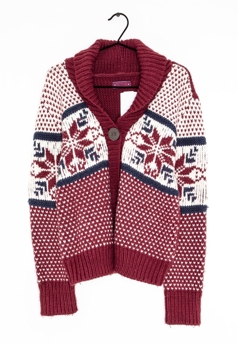 Cardigan tricoté bordeaux, blanc et bleu marine avec de grands motifs flocons de neige, col et poignets côtelés, bouton unique à l'avant, accroché à un cintre noir.