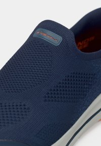 Ναυτικό slip-on παπούτσι με υφασμάτινο άνω μέρος με υφή, πάνελ από δίχτυ, και ελαστική σόλα με επένδυση μαξιλαριού, με το λογότυπο "GO WALK".