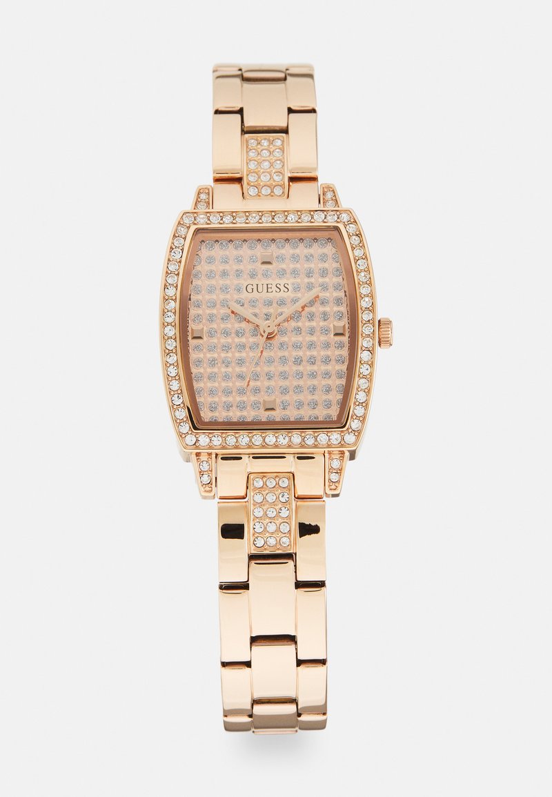 Rektangulær rose-guld ur med en krystalkant, tekstureret pink urskive og metalled. Den har diskrete timemarkører og visere.