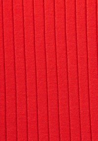 Tissu rouge côtelé avec une texture verticale, fabriqué à partir d'un tissu tricoté, présentant des lignes surélevées régulièrement espacées créant un motif uniforme.