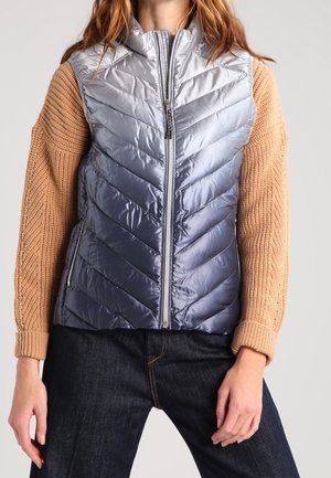 Gepolstertes Weste mit einem silbernen Ombre-Finish, das ein Chevron-Muster aufweist, hohen Kragen und gestrickten, hellbraunen Ärmeln. Reißverschluss und seitliche Taschen.