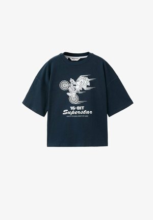 Maglietta blu navy con Sonic the Hedgehog che fa una ruota su una bici, con la scritta "16-BIT Superstar" e "Sonic è il nome, la velocità è il mio gioco!"