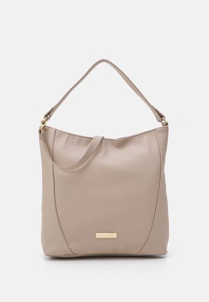 Beżowa skórzana torebka z teksturowanym przednim panelem, pojedynczym górnym uchwytem i małą złotą plakietką z logo na środku u dołu.