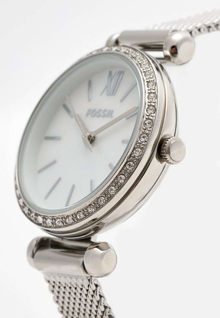 Orologio da donna Fossil con cinturino in maglia argentata, quadrante rotondo bianco, bezel decorato con cristalli e indicatori delle ore argentati. Presenta una corona liscia.