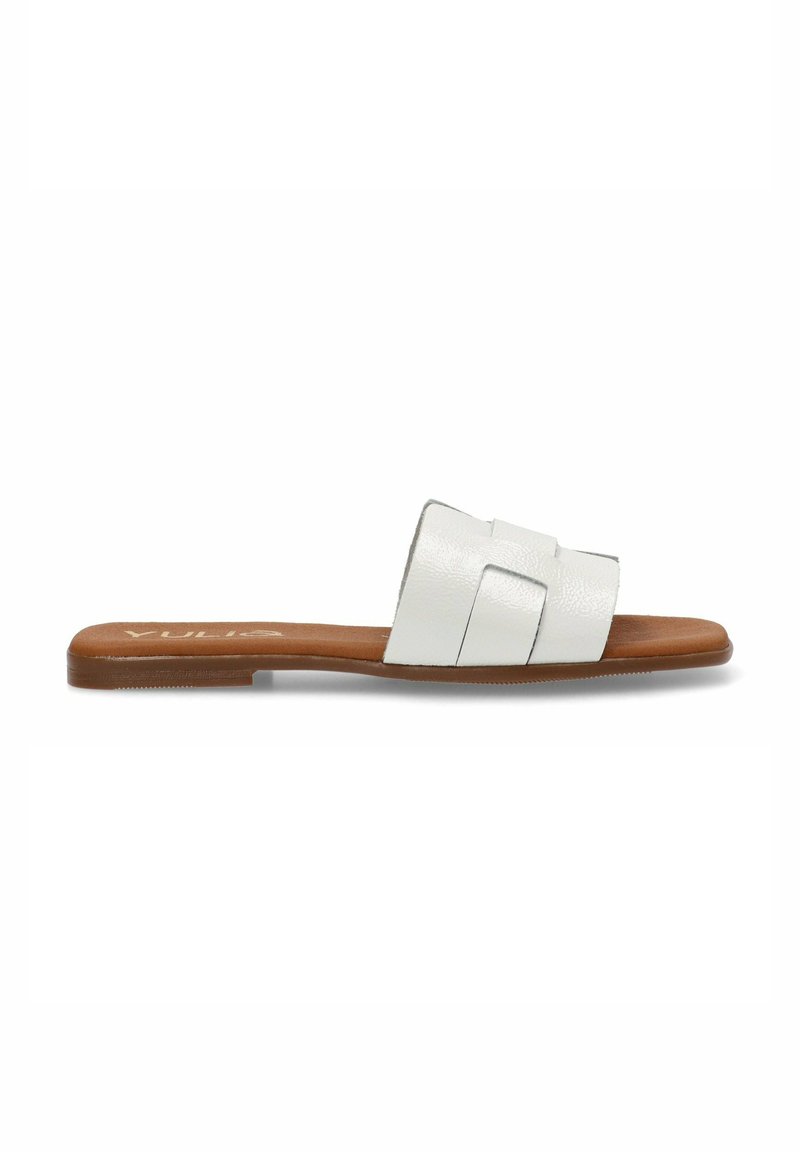 Sandalia deslizante de cuero blanco con tres tiras texturizadas y una suela plana marrón. Presenta un diseño minimalista para uso casual.