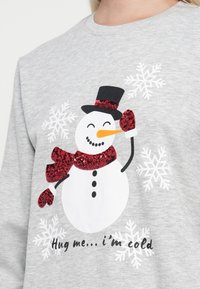Szary sweatshirt z grafika bałwanka w czarnym kapeluszu, czerwonej szaliku i rękawiczkach. Białe płatki śniegu i tekst poniżej. Miękka struktura.