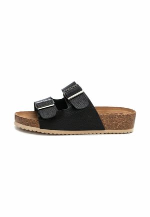 Sandalia negra de dos correas con parte superior texturizada, hebillas de hardware plateado, plantilla de corcho y suela exterior de goma beige con un patrón ondulado.