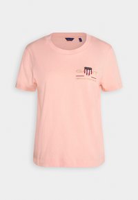 T-shirt rose clair en coton, avec un col rond, des manches courtes et un logo brodé sur la poitrine.