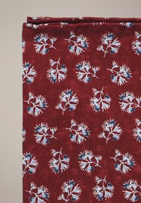 Bawełniana tkanina w głębokim czerwonym kolorze z kwiatowym wzorem; niebieskie i białe kwiaty z misternymi detalami; delikatnie teksturowana z subtelnym połyskiem.