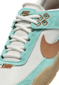 Nike tenisky s bielou sieťovinou, akcentmi v odtieni akvamarínu, semišovým prekrytím, svetlohnedým brandingom a textúrovanou gumovou podrážkou.