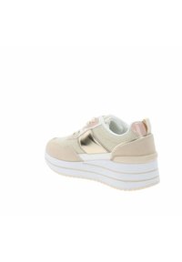 Zapatilla de color beige claro con malla y acentos metálicos. Cuenta con una gruesa suela blanca y una lengüeta trasera rosa, que muestra un diseño en capas.