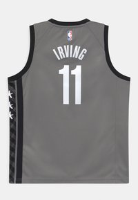 Camiseta de baloncesto gris con cuello redondo, detalles negros y letras blancas que dicen "IRVING" y el número "11". Patrón de estrellas en el lateral.