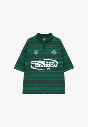 Polo rayé vert et vert foncé avec col vert foncé, patte de boutonnage, texte "CORE DIVISION" et deux petits logos blancs sur la poitrine.