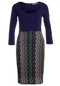 Granatowa bluzka dopasowana z okrągłym dekoltem, przechodząca w spódnicę w wzory w odcieniach zieleni, czerwieni i kremu, z teksturowanym wzorem.