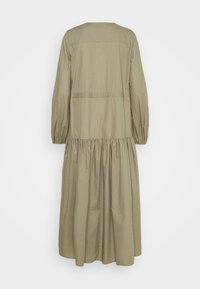 Lungo vestito beige con maniche lunghe, vita arricciata e gonna leggermente svasata, mostrato di spalle su uno sfondo bianco.