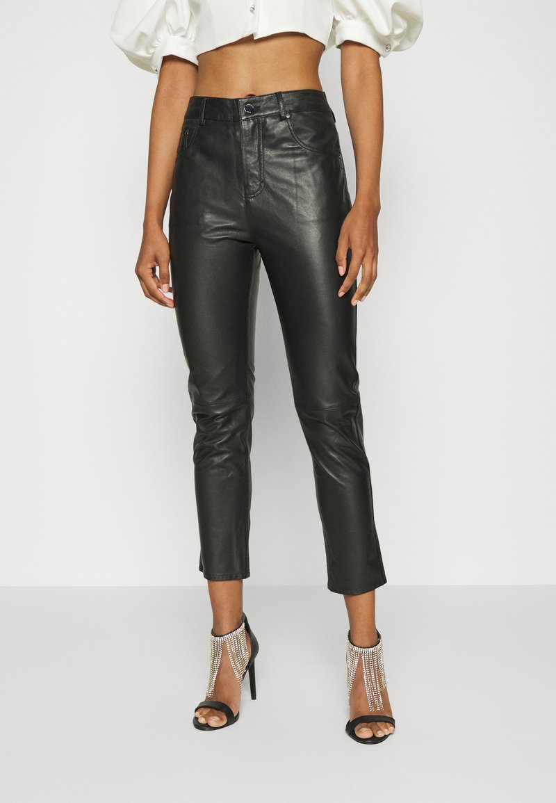 Svarta läderbyxor med slim fit, kort längd och subtil lyster. Matchas med svarta öppna tå-klackar med juvelerade ankelaccent.