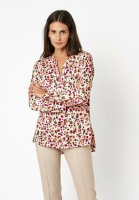 Bluse mit Blumenmuster in Hellrosa mit lila und braunen Akzenten, ohne Kragen, langen Ärmeln und geradem Schnitt. Glattes Material.