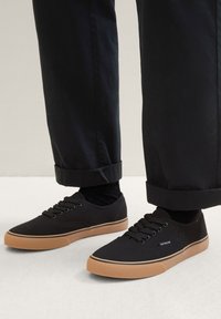 Sneaker nere in tela con suola in gomma testurizzata, caratterizzate da punte arrotondate, design con lacci e logo discreto sul lato.